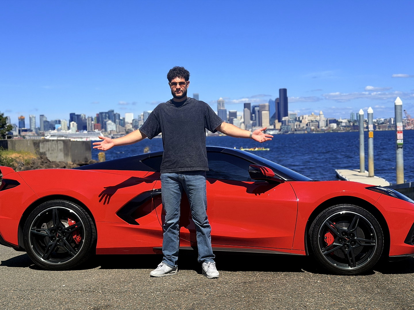 Joshua Daniels with a red Corvette and the Seattle skyline