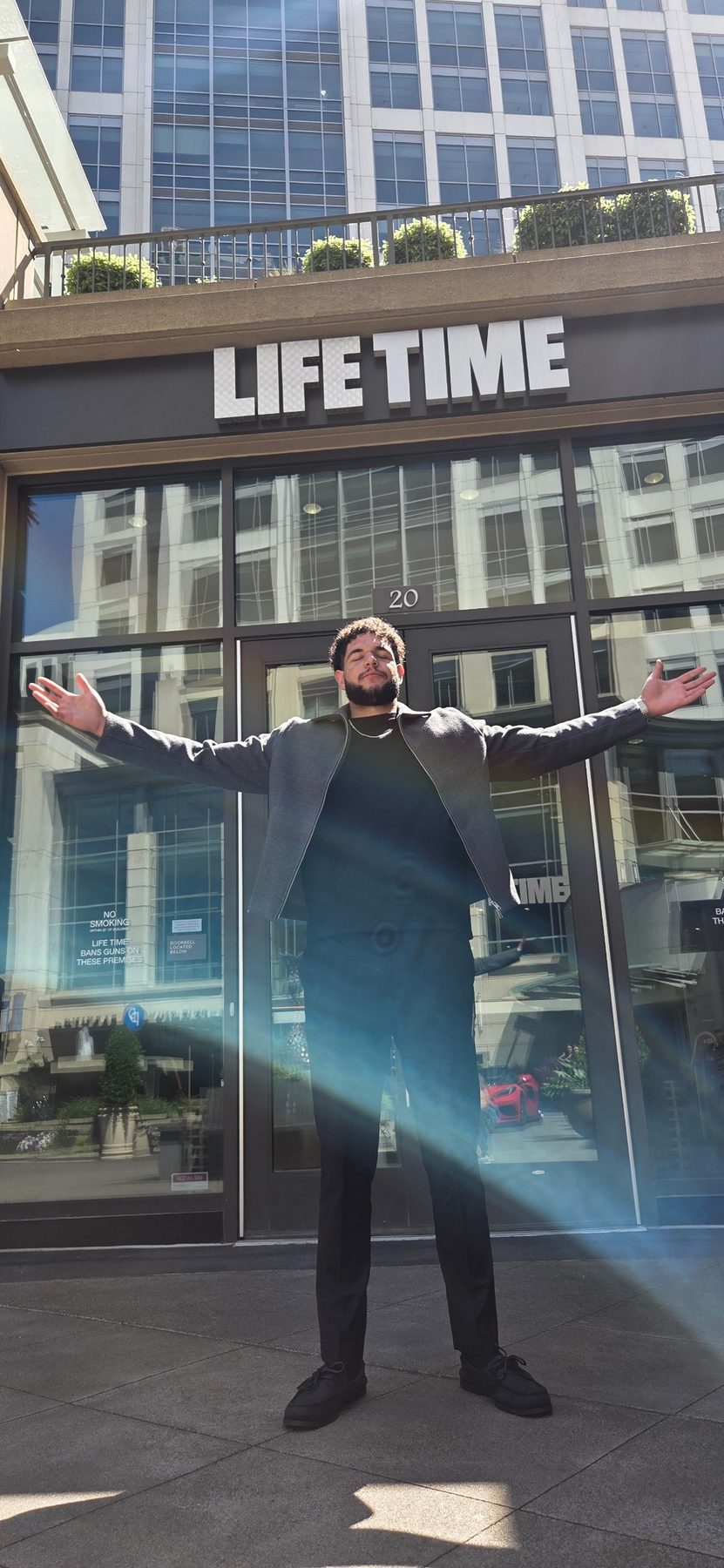 Joshua Daniels arms-wide outside the Life Time building